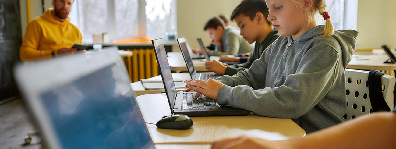 Klassenzimmer mit Kindern die an Laptops lernen